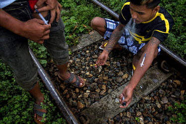 Drug users prepare to inject heroin, one is injecting into his groin, while sitting on some railway tracks. Kachin state, where most of Myanmar's jade comes from, has some of the highest rates of hero...