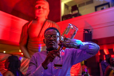 A man pours a glass of Hennessy Cognac at the Spice Route night club on Victoria Island.
