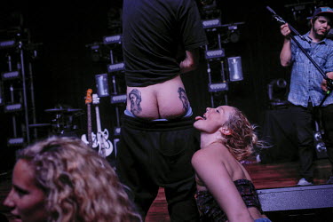 A young woman poses for a photograph with the lighting technician from Nashville based electro-pop duo Cherub. The tattoos on his buttocks are of Jason and Jordan, the band's musicians.