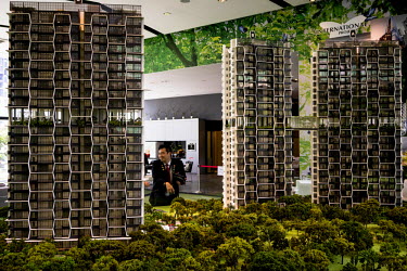 A salesman shows off the architectural models for high-rise serviced apartments that boast many sustainable-living features including a number of sky parks and hanging gardens.  With a growing urban p...