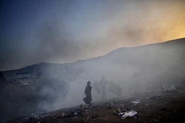 Children scavange at a landfill site east of Freetown where rubbish is burning.