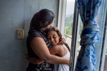 Esica Garcia Acevedo, 32, with her daughter, Migadnia, 8, looks out the window of their flat in Nuevo Occidente, a massive social housing complex of mostly displaced or forcibly evicted families in Me...