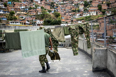 A member of an army unit stationed in Comuna 13, the most dangerous district in Medellin, walks between washing lines on the roof of one of the buildings. There are eight bases with 140 soldiers in th...