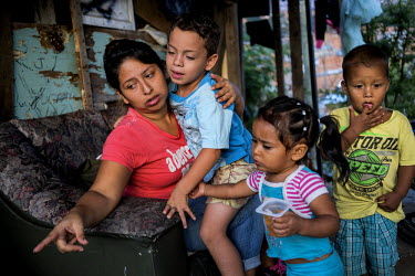 Marta Chica Lopez, 27, points to a dead chick near the chicken coop. Her son, Juan Esteban, 6, left sits on her knees. Her daughter Luciana, 2, center, and nephew, right also look on at their home in...
