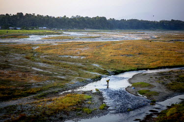 A man walks across a flat landscape next to the Mechi bridge which connects India and Nepal near the Panitanki border post. The border point is one of the main smuggling routes for tiger parts traffic...