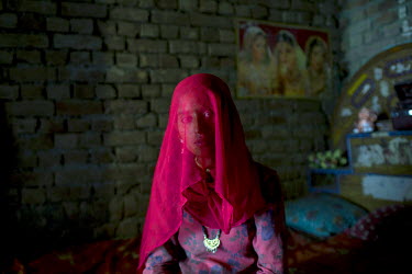 A Babaria woman with her head covered by a pink headscarf sits in her house. The Babaria are a major source of illegally traded tiger parts since they used to hunt them when it was legal to do so and...