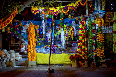 A man sits next to a market stall is decked out in colourful flowers on the occasion of Diwali, one of the biggest festival for Hindus.