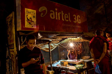 A man looks at his mobile phone next to a food stall in the Manaju Ka Tila district, a Tibetan refugee neighborhood, in Delhi where Tigers parts are traded according to the Wildlife Crime Control Bure...