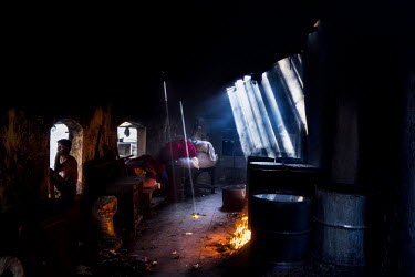 Sanjay, a dhobi (washerman), seeks a little breeze while he speaks on the phone in a building where cauldrons of water and chemicals are brought to the boil on open fires. Dhobighat is an open air are...