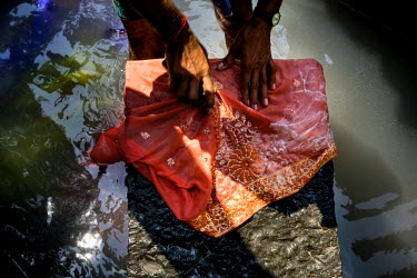 A dhobi (laundry person) washes a delicate embroidered sari on a flogging stone in Dhobighat. This is an open air area where 'dhobis' wash the laundry for all strata of the city's society. It is here...