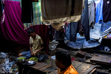 A man chops vegetables for a meal in Dhobighat, the open air area where the city's laundry is washed by an army of dhobis (laundry person). It is here that the laundry for all strata of the city's soc...