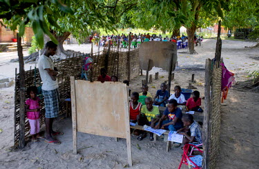A primary school class held outside beneath the shade of trees in Betame.