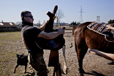 Tomasz, a member of paramilitary association Strzelec (The Shooter), saddles a horse at his girlfriend's ranch. Since the start of war in Ukraine, paramilitary groups have seen a rise in membership.