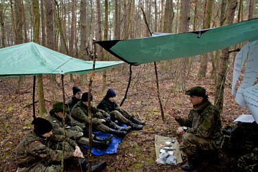 Tomasz, right, instructor and member of Strzelec (The Shooter), a paramilitary association, teaches recruits during survival training in a forest. Since the start of war in Ukraine, membership of para...