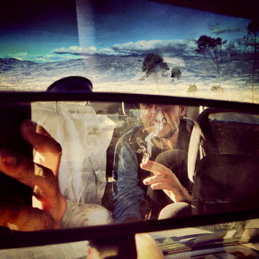 A man smokes in the back of a car on top of Ilalo, an extinct volcano.