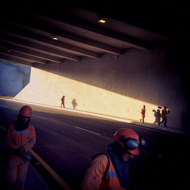 Workers walk through a tunnel which is part of the Ruta Viva (Living Road), a six-lane highway that connects the city and the airport.