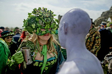 A woman holding a tankard speaks to a man painted white at a Jack in the Green Festival.  The festival is part of a recent revival of an older custom where people would wear frameworks covering much o...