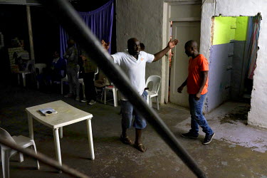 On Wednesday evenings George Khosi (left), founder of the Hillbrow Boxing Club, runs a prayer meeting in the club's basement. After gunshot injuries from a home invasion put an end to his own boxing c...