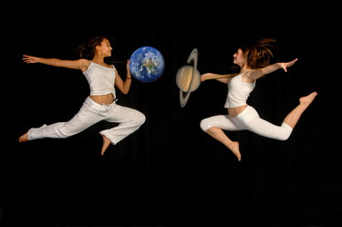 Twi schoolgirls dancing with models of the Earth and Saturn at a secondary school in Yorkshire. They are dancing as part of a project that combines astronomy with the performing arts.