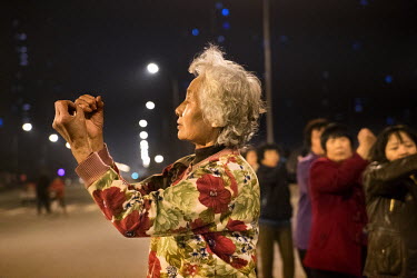 A woman takes part in <i>Guang chang wu</i> or 'public space dance' with other local residents in a 'replacement' housing estate for farmers who have lost their land. In a move to increase the size of...