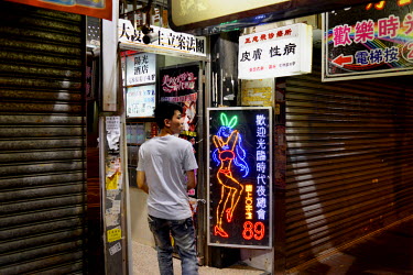 A man entering a typical multi-use tenement building in the working class and imfamously seedy Mongkok District.