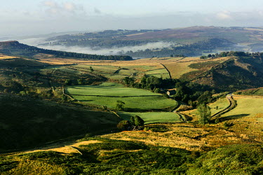 Mist lies over the forest and grazing fields seen from Stanage Edge.