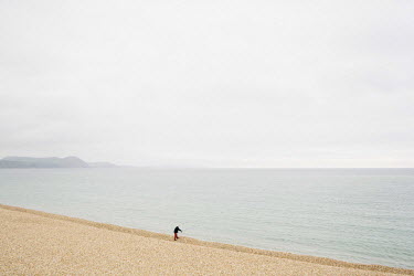 A man fishing (beach casting) from the shingle beach at Lyme Regis.
