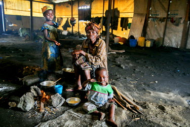 A newly arrived IDP and her children sit by a fire and rest after completing an exhausting journey to Bulengo IDP camp.