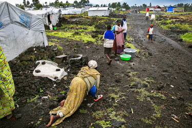 A disabled woman drags herself over the rocky volcanic soil in search of food at Bulengo IDP camp.