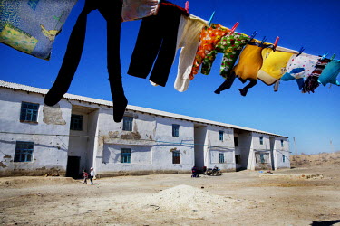 Washing hangs from a line outside a run-down housing complex. The town is within the catchment area of the Amu Darya river delta that once supported an extensive irrigation based agricultural system....