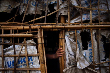 A woman holds her tattered tent made from bamboo and discarded relief aid sacks in the Thae Chaung Rohingya IDP camp, established after violent clashes between Muslim Rohingya and Budhhist Rakihine ex...