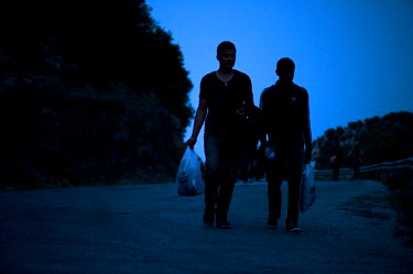 A group of around 50 Afghans - men, women and children - walk the nine hour distance from Skala Sykaminias to the village of Moria on the island of Lesbos where the First Reception Centre for refugees...