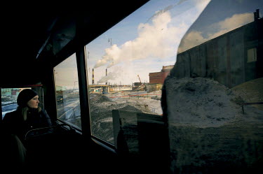A woman looks out of the window of a bus as it drives along a road in the Greater Norilsk area. Greater Norilsk consists of three settlements: Norilsk, Talnakh and Kayerkan, all within a radius of 30...