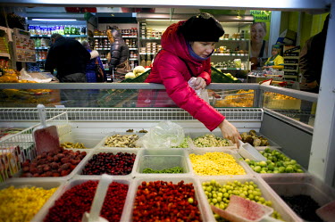 A young woman picks frozen vegetables out of a freezer in a grocery shop in Norilsk. All fresh fruit and vegetable has to be imported and therefore is expensive. Frozen fruit is an alternative for man...