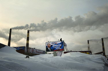 A man works on a billboard which displays a poster that reads: 'V. Putin 2012 - Together for a Great Russia' next to a factory in Norilsk.  The city of Norilsk, in the far north of Russia's Krasnoyars...