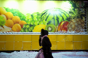 A woman in a fur jacket walks past a large billboard showing fresh fruit in Norilsk.   The city of Norilsk, in the far north of Russia's Krasnoyarsk region, was founded in the 1920s and today has a po...