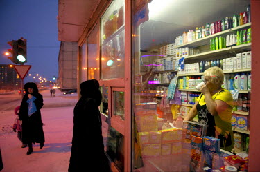 A woman stands by a small window of a shop in Norilsk while the shop keeper inside drinks a cup of tea.  The city of Norilsk, in the far north of Russia's Krasnoyarsk region, was founded in the 1920s...