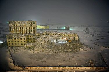 A bulldozer demolishes a building at night in Norilsk on an icy night. The city is facing an infrastructural crisis since most of the buildings were built on pylons driven into permafrost. As the top...