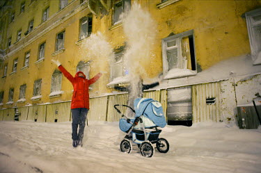 A woman with a pram throws a handful of snow into the air in front of an old building in Norilsk.  The city is covered in snow for around 8 to 9 months a year. Each year around 10 tonnes of snow fall...