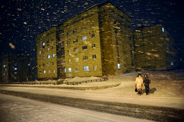 Residents walk past an apartment block in Norilsk at night during a snow drift. The city is covered in snow for around 8 to 9 months a year. Each year around 10 tonnes of snow fall on the city for eac...