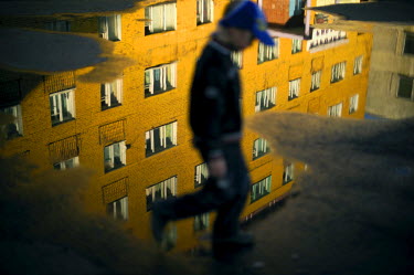 A boy walks past a puddle in a residential area of Norilsk during holiday time.  Most children are sent to 'the mainland' (ie Russia proper) to their grandparents for their holidays or they go to holi...