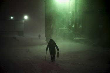 A resident walks past a dimly lit aparment block in Norilsk in a snowdrift. The city is covered in snow for around 8 to 9 months a year. Each year around 10 tonnes of snow fall on the city for each in...