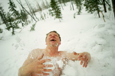 A man rolls around in the snow as part of the so-called 'Walrus' club. A popular past time is to take a dip in holes cut into the ice and then retire to a 'banya' (or sauna) which is heated with steam...