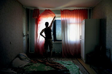 A man closes the thin curtains of his bedroom at night during the polar summer when the sun doesn't set for over 45 days.  The city of Norilsk, in the far north of Russia's Krasnoyarsk region, was fou...