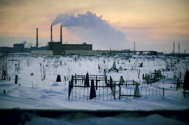 Grave stones in a cemetery are seen against the backdrop of one of the smelters in Norilsk. According to Pure Life (formerly Blacksmith Institute) the life expectancy in Norilsk is 10 years less than...