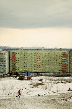 A man walks down a hill toward a residential apartment block in the city of Norilsk.  The city is covered in snow for around 8 to 9 months a year. Each year around 10 tonnes of snow fall on the city f...