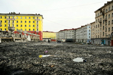 A man walks across a street covered in black slush. When spring arrives in Norilsk, the snow that has accumulated over the winter melts, leaving slush and large puddles.  The city of Norilsk, in the f...