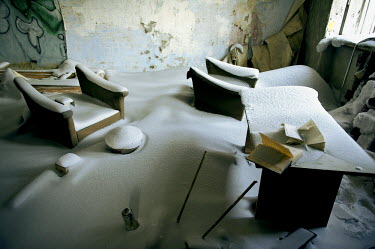 The interior of an abaondoned multi storey building in Norilsk covered in snow with pieces of abandoned furniture.   The city is facing an infrastructural crisis since most of the buildings were built...