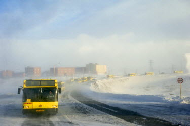 A caravan of public buses travels in convoy during a snow storm taking workers from their homes to work within the Greater Norilsk area. If one bus breaks down the passangers can be absorbed by anothe...