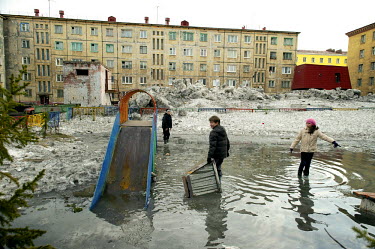 Children play in puddles which appear suddently with the arrival of spring when huge quantities of snow melt. The winter in Norilsk can last the best part of nine months.  The city of Norilsk, in the...